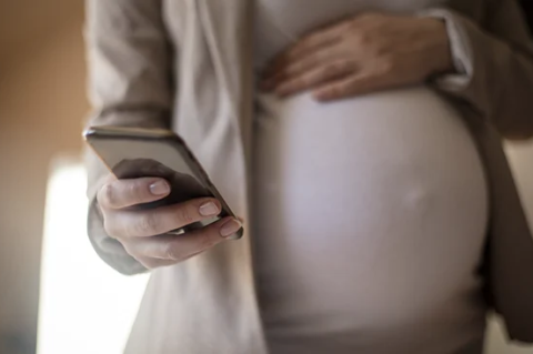 birthing person holding stomach with phone